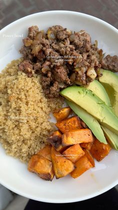 a white plate topped with meat, rice and sweet potato wedges next to an avocado