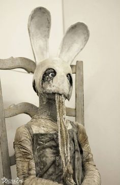 a statue of a rabbit sitting in a chair with its head turned to the side