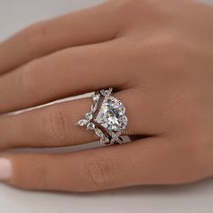 a woman's hand with a diamond ring on top of her finger and an engagement band