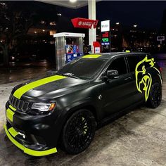 a black and yellow car parked in front of a gas station