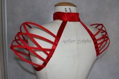 a white mannequin with red ribbon on it's back and neckline