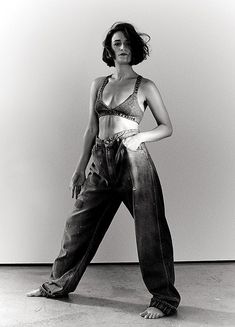 a black and white photo of a woman in high waisted jeans posing for the camera