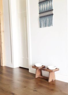 two bowls are sitting on small wooden benches in front of a white wall and door