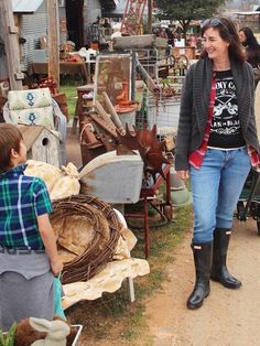 a woman standing next to a little boy in front of a yard full of junk