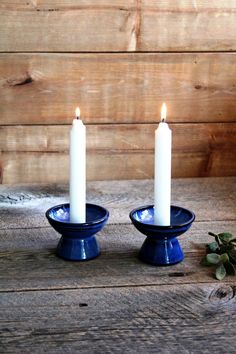 two white candles sitting on top of blue dishes