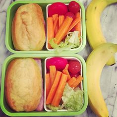 three plastic containers filled with food on top of a marble counter next to two bananas