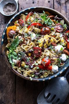 a bowl filled with pasta and vegetables on top of a wooden table