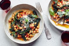 two plates of food on a table next to glasses and silverware with red wine