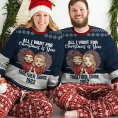 two people wearing matching christmas sweaters and pajama pants sitting next to each other