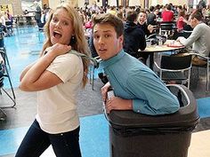 a man and woman standing next to a trash can