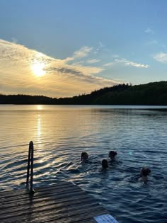 some people are swimming in the water at sunset