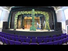 an empty stage with purple chairs and curtains