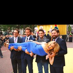 a group of men and women posing for a photo with a woman on her back