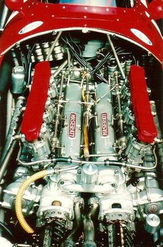 the engine compartment of an old race car with red trimmings and chrome parts