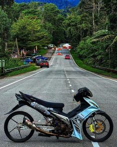 the motorcycle is parked on the side of the road with mountains in the back ground