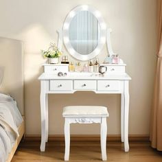 a white dressing table with a mirror and stool next to it on a wooden floor