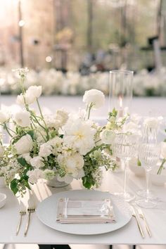 a table set with white flowers and silverware