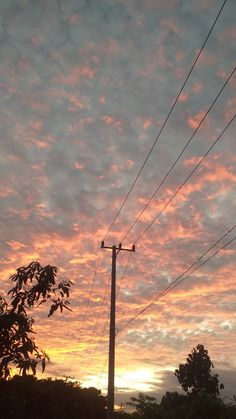 the sun is setting behind power lines and telephone poles