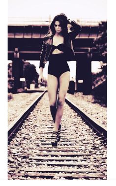 a woman is walking down the train tracks