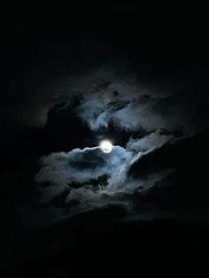 the moon is shining brightly in the dark night sky with fluffy clouds and black skies