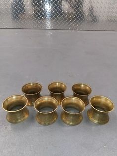 nine brass bowls are lined up on the floor