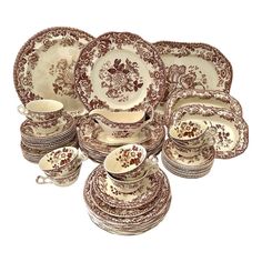 an assortment of antique china plates and cups, all decorated in brown floral designs with gold trimmings