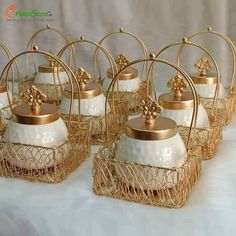 gold and white glass teapots with golden metal wire holders on a white tablecloth