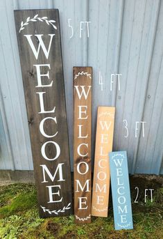 three wooden welcome signs sitting next to each other