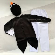 an infant's black and white outfit is laying on the ground next to a stuffed animal