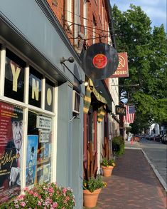 a storefront with flowers in front of it on the side of a street next to a brick building