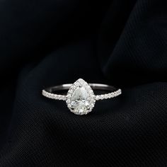 a pear shaped diamond ring on a black cloth