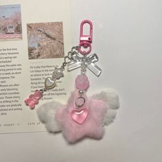 a pink teddy bear keychain with hearts and keys attached to it's back