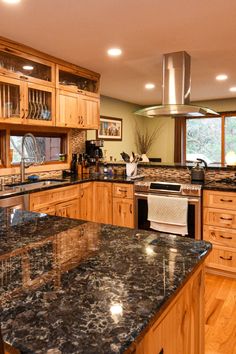 a large kitchen with granite counter tops and wooden cabinets, along with stainless steel appliances