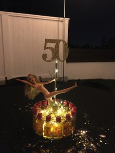 a woman is standing on top of a birthday cake with candles in the shape of a 50