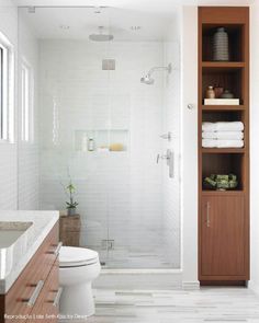 a bathroom with white tile and wooden cabinets