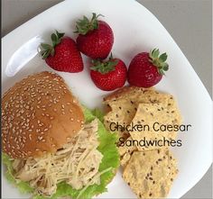 chicken caesar sandwiches with lettuce and strawberries on a white plate next to crackers