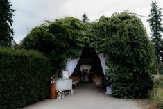 an outdoor wedding venue with white draping and greenery on the side walk