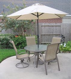 a patio table with chairs and an umbrella in the middle of a back yard area