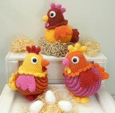 three crocheted chickens sitting next to each other on top of a white shelf