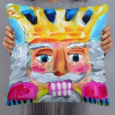 a person holding up a pillow with a painting on it