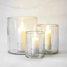 three clear glass vases with lit candles in them