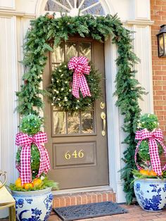 two pots with wreaths and bows on the front door