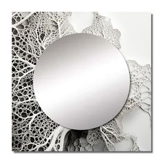 a round mirror sitting on top of a white table next to an intricate lace doily