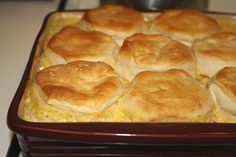 a casserole dish with biscuits in it sitting on a stove top next to an oven