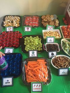 a table filled with lots of different foods and snacks on it's sides, including carrots, grapes, apples, nuts, and more