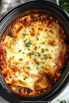 an overhead view of a crock pot filled with lasagna sauce and cheese