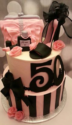 a pink and black cake decorated with high heel shoes, purses, and pearls