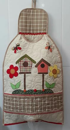 an oven mitt with birds and flowers on the front is hanging from a hook