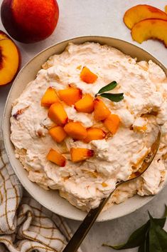 a bowl filled with peaches and whipped cream next to sliced peaches on a table