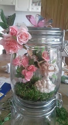 a glass jar filled with pink flowers and fairy figurines